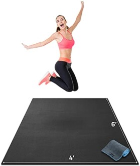 Person jumping on a black workout mat with towel.